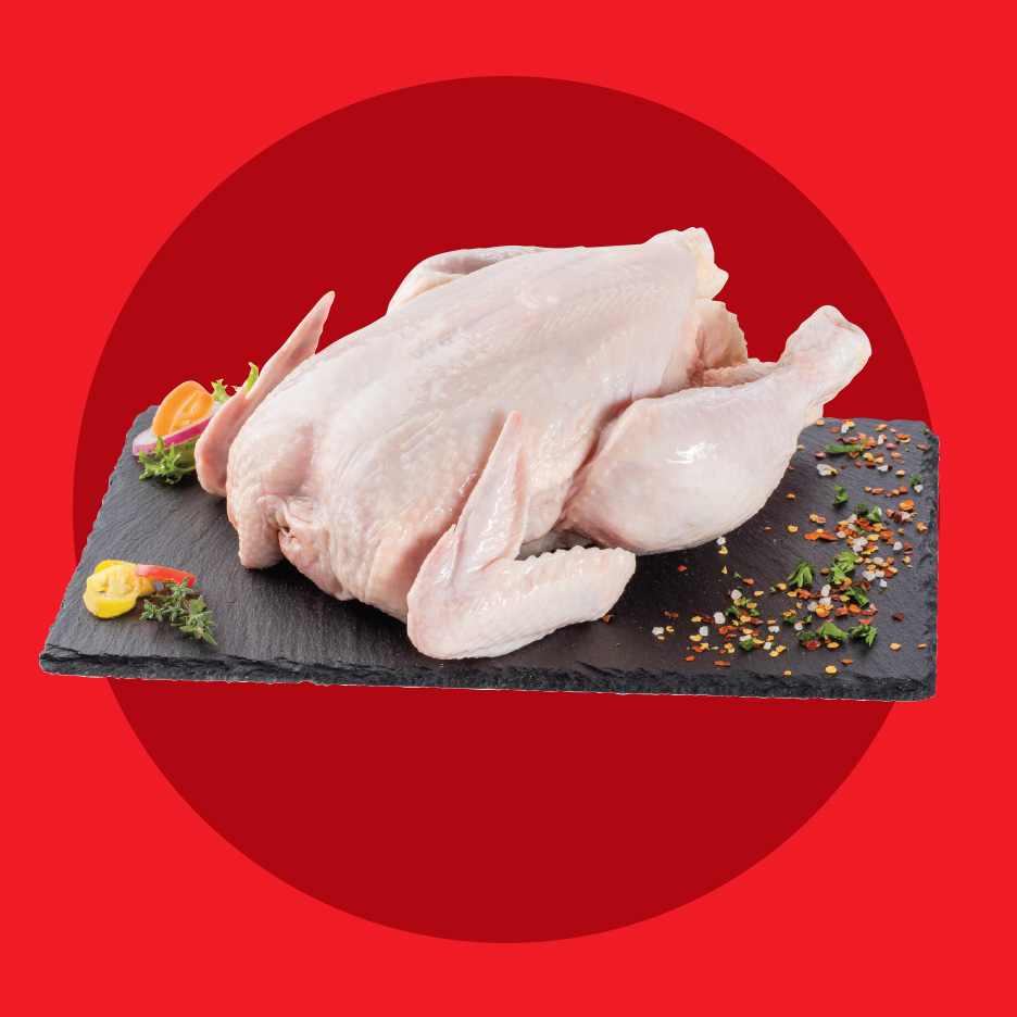 Sveže celo pile na crnoj ploči sa začinima i povrćem.