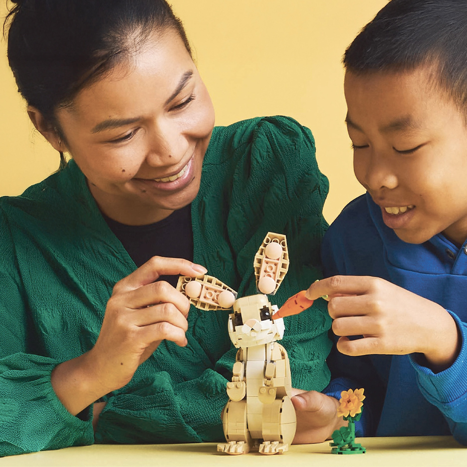 Žena i dečak se igraju sa igračkom zeca i šargarepom od kockica.