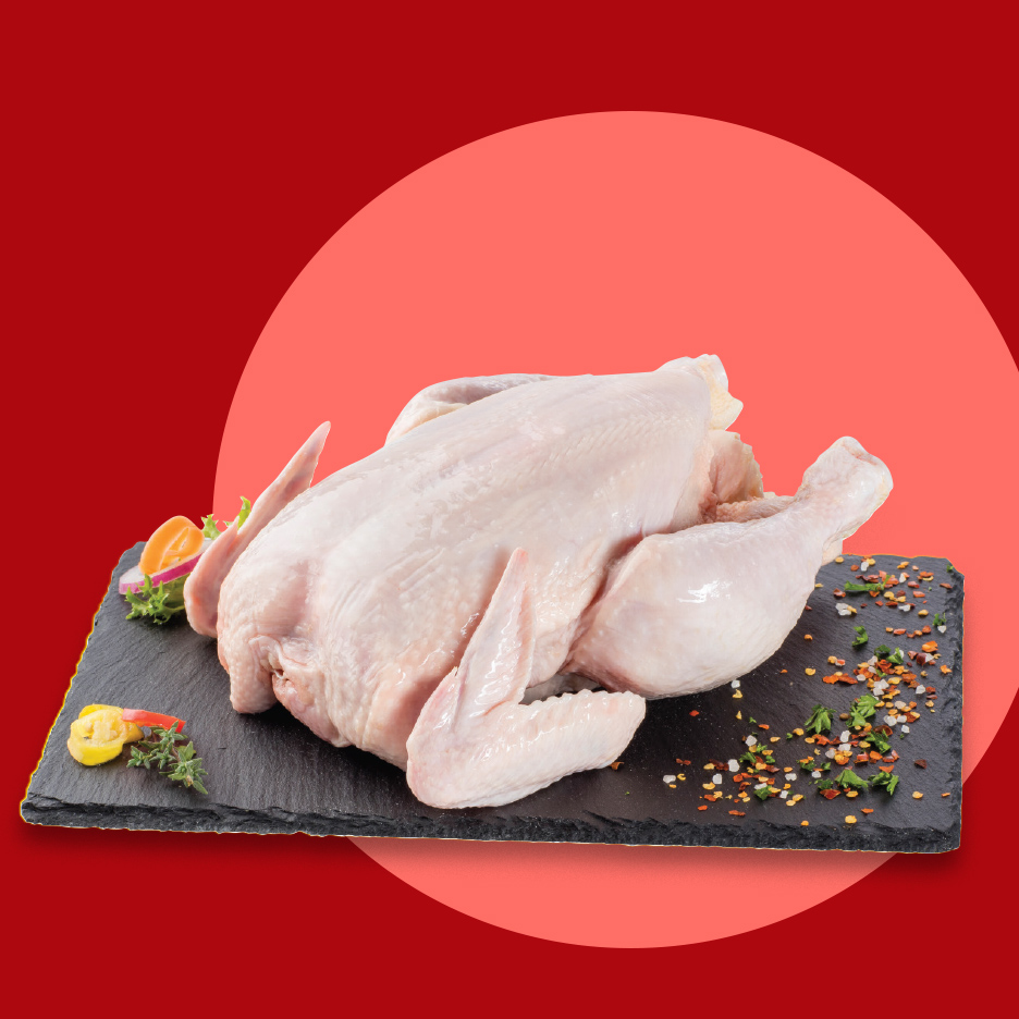 Sveže celo pile na crnoj ploči sa začinima i povrćem.