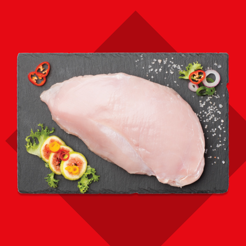 Sveža pileća prsa na crnoj ploči sa začinima i voćem.