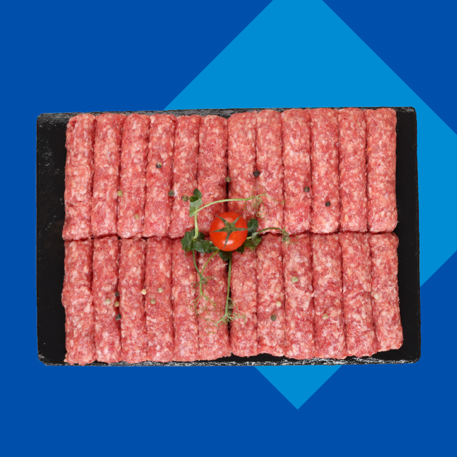 Sveži ćevapi na crnoj tacni, ukrašeni paradajzom i začinskim biljem.