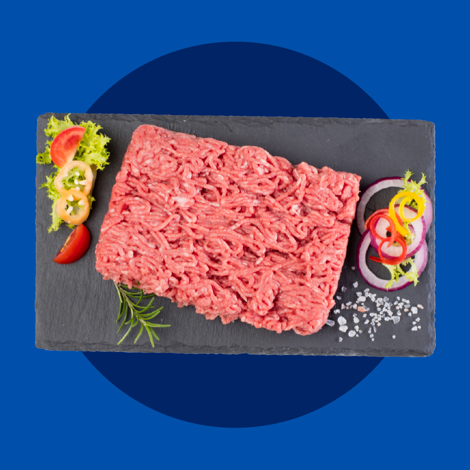 Mleveno meso sa začinima i povrćem na crnoj ploči.