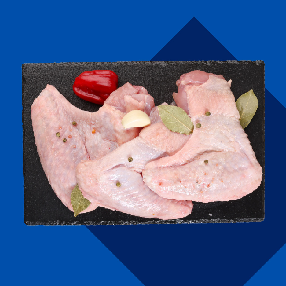 Sveža pileća krilca sa belim lukom, lovorovim listom i crvenom paprikom na crnoj ploči.