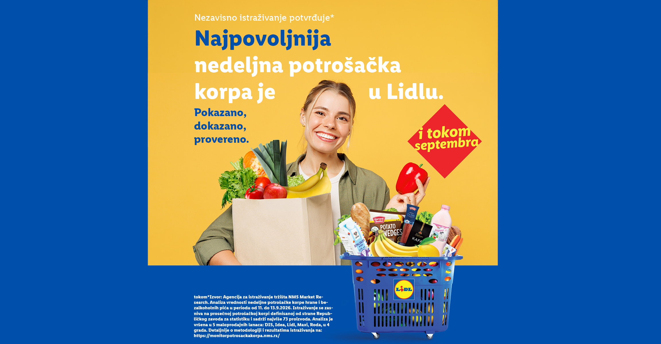 Žena drži papirnu kesu sa svežim voćem i povrćem pored plave korpe pune namirnica.