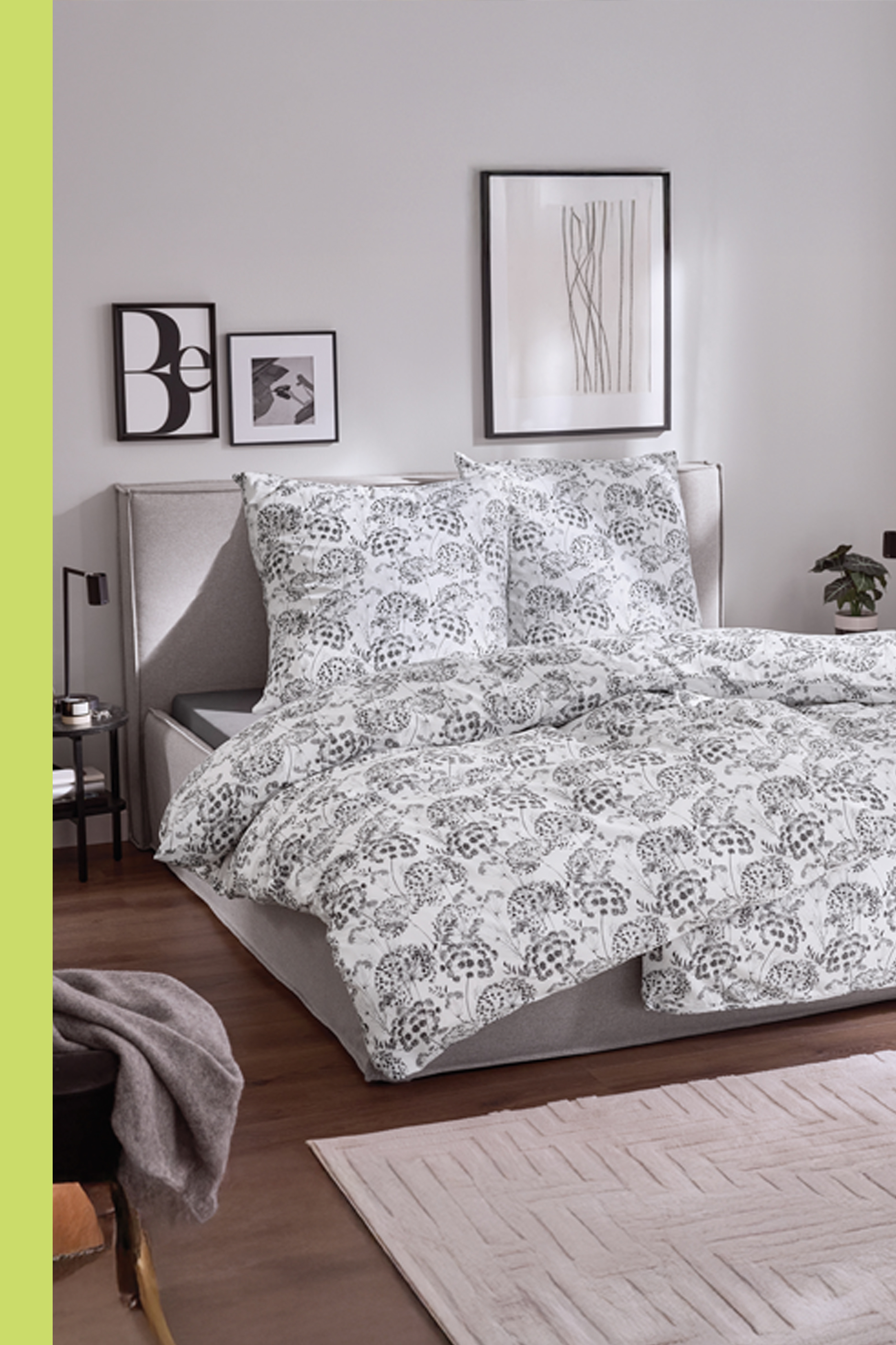 Spavaća soba sa krevetom, posteljinom sa cvetnim dezenom, noćnim stočićem i tepihom.