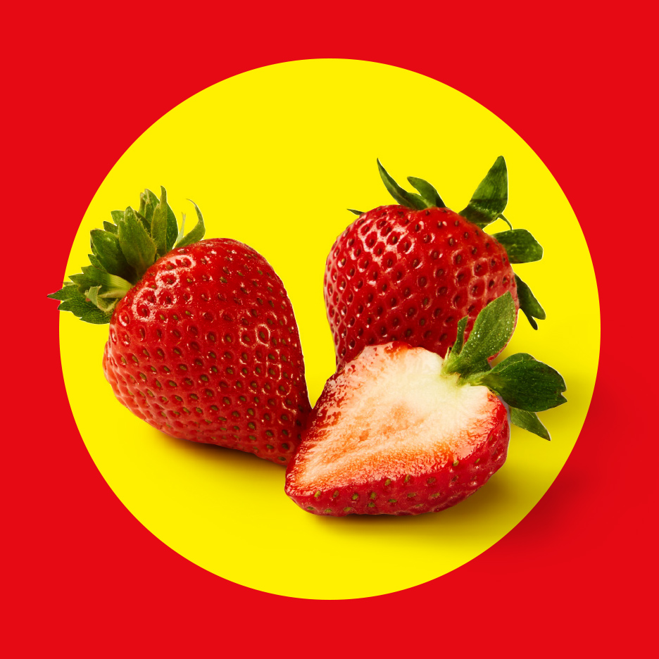 Tri sveže jagode, jedna prepolovljena, na žutoj pozadini sa crvenim okvirom.