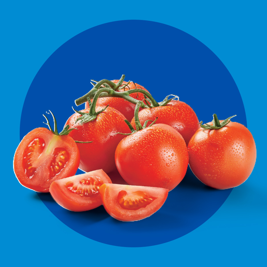 Sveži crveni paradajz sa kapljicama vode, ceo i isečen, na plavoj pozadini.