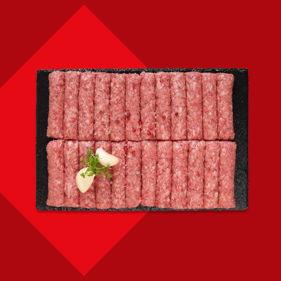 Sveži ćevapi na crnoj ploči sa belim lukom i peršunom.